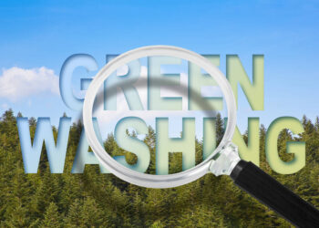 Alert to Greenwashing - concept with text against a woodland and magnifying glass