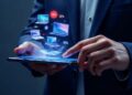 Businessperson using a tablet with floating holographic laptops and percentage icons indicating data/connection. l